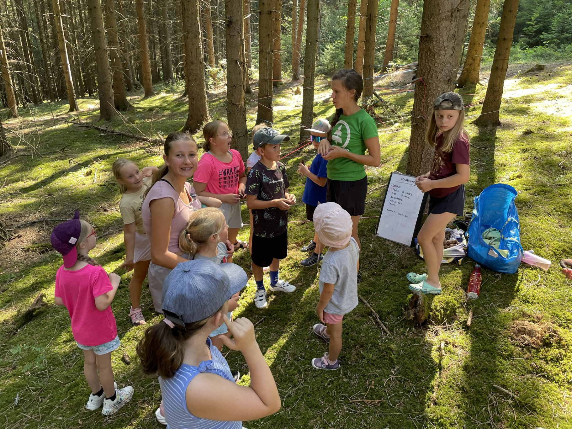 Lektorka vysvětluje dětem anglická slovíčka v lese u tabule